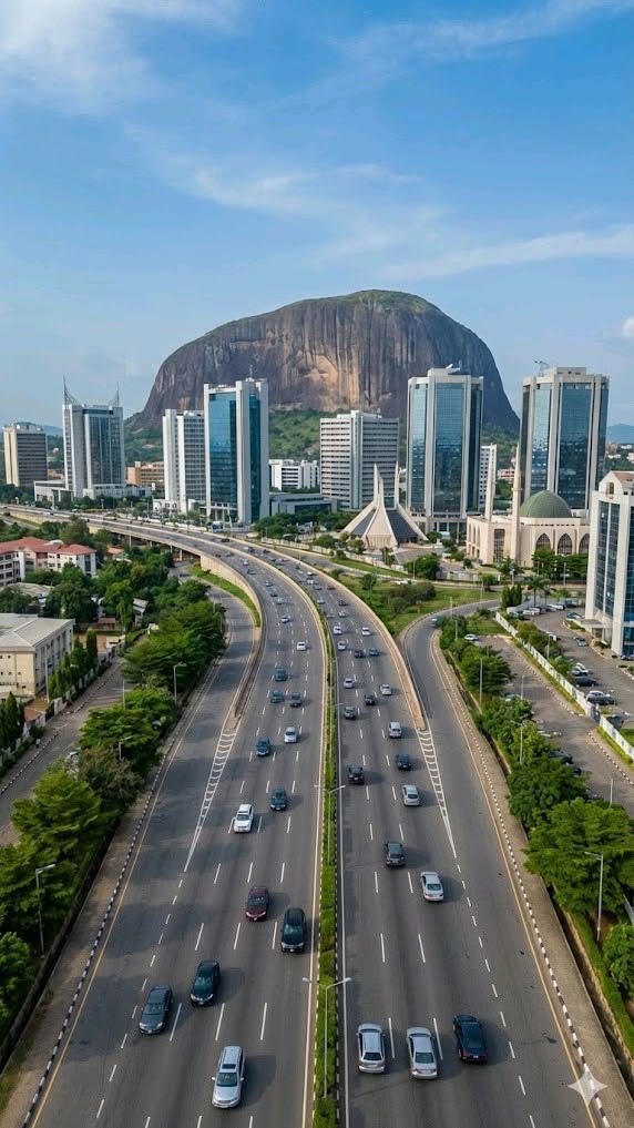 Highway leading into Abuja’s city center, with office towers and a large rock formation behind them